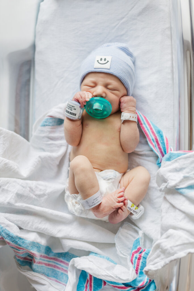 Newborn baby boy lying on a soft blanket, with a gentle light illuminating his features in the UAB Hospital nursery