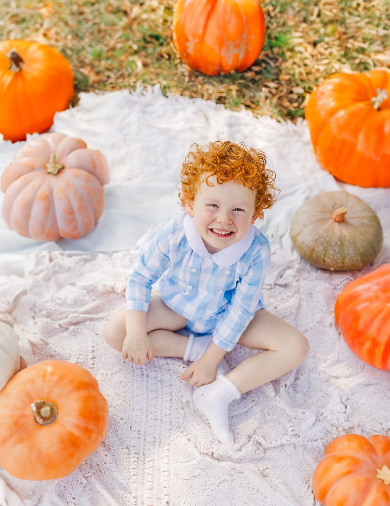 Child exploring the pumpkin patch during a fall family session at Old Baker Farm