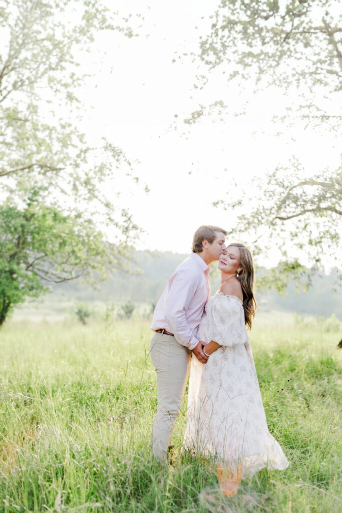 Pregnant mom standing in grassy meadow with husband in floral dress during maternity session outside of Birmingham Alabama with 5U Photography