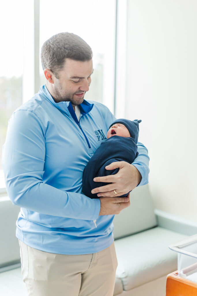 Dad gently holding newborn baby James in a quiet, tender moment during a Fresh 48 session at Grandview Medical Center in Birmingham, AL