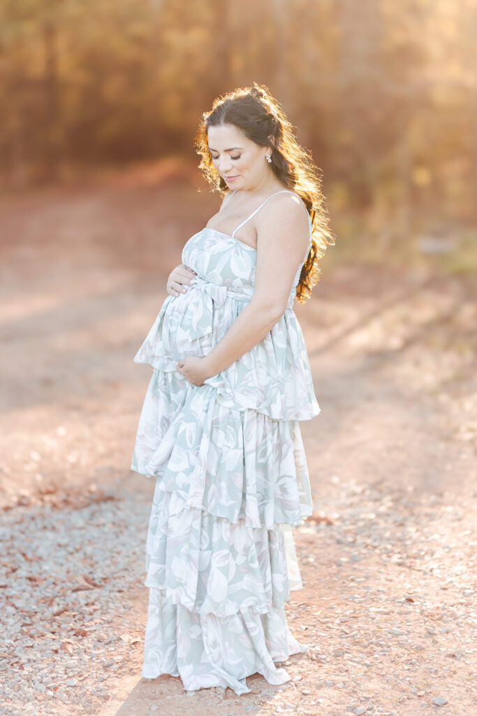 Expecting mother posing in a fall maternity session at Old Baker Farm, Birmingham, AL, with golden autumn leaves in the background