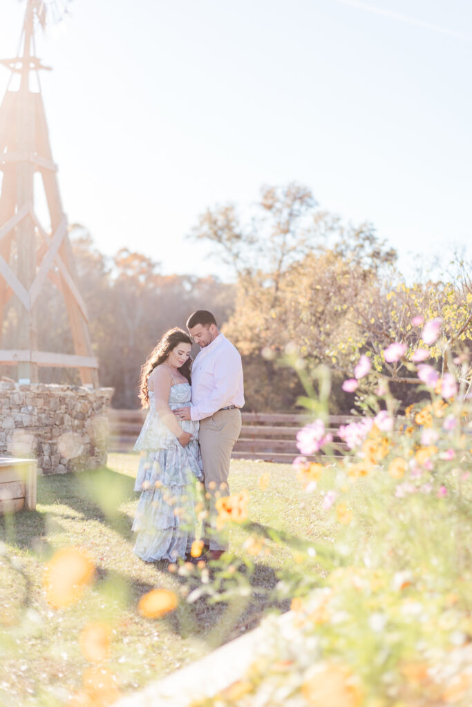 Expecting couple walking hand-in-hand through a picturesque fall field during their maternity session at Old Baker Farm in Birmingham, AL