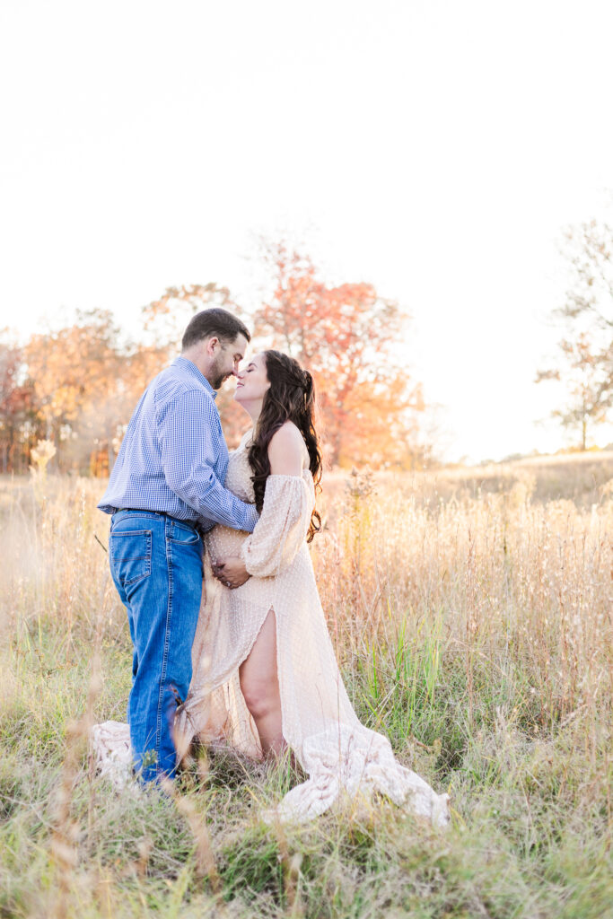 Family maternity photoshoot in a private boho field, with vibrant fall leaves and soft sunlight highlighting the expecting parents