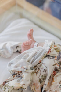 close up of babies feet lying in hospital crib with hospital bracelet on baby's ankle 