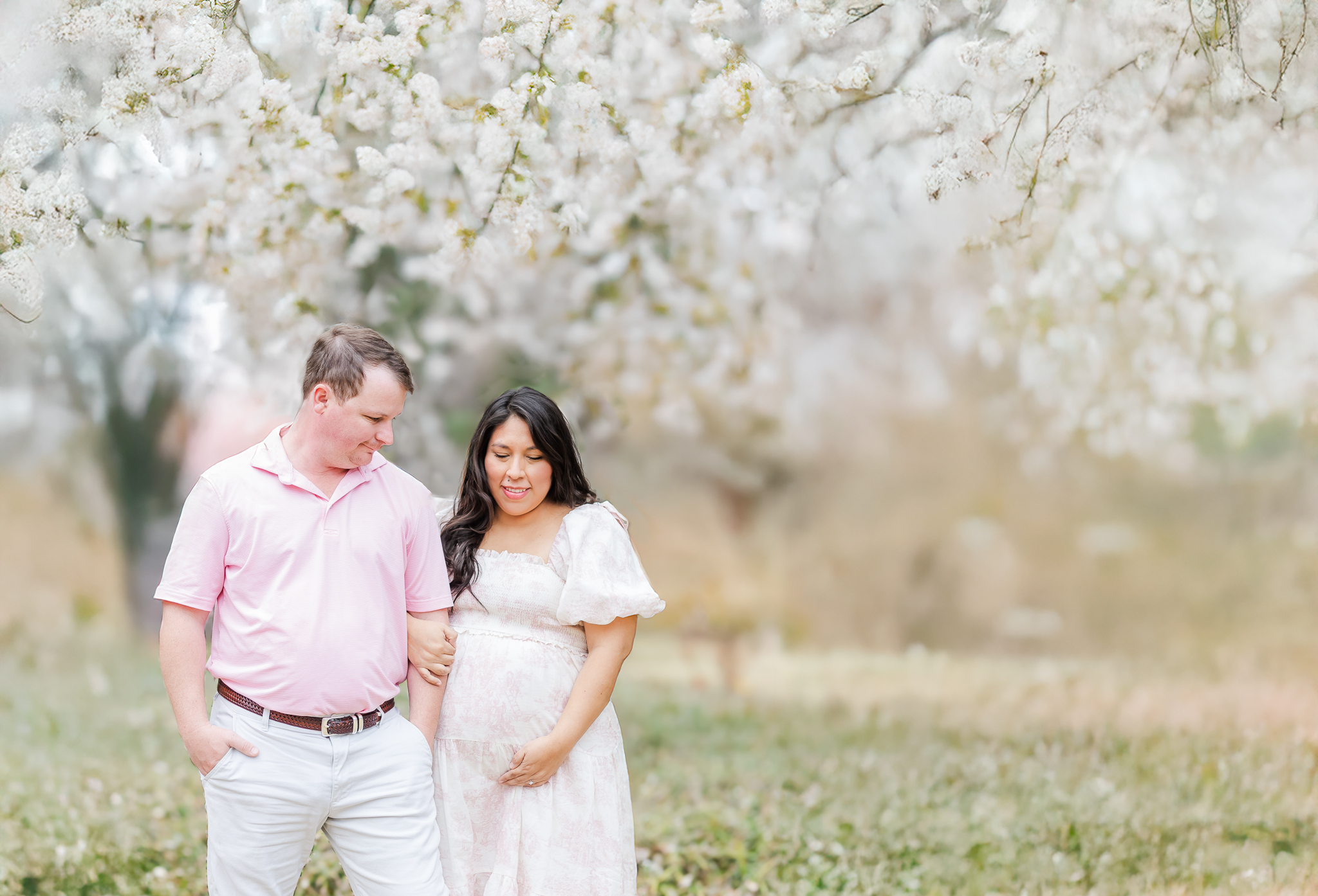 Giddens family smiling in front of blooming cherry blossoms during their spring maternity session at Birmingham Botanical Gardens