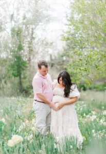 Giddens family in coordinated pastel outfits, standing amidst a sea of blooming tulips at the botanical gardens during spring maternity session