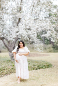 Expecting mother gazing at the flowers around her, with a serene and peaceful expression on her face during session with 5U Photography