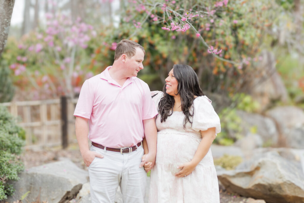 Giddens family laughing together as they pose in front of the blossoming cherry trees at the Birmingham Botanical Gardens during spring maternity session