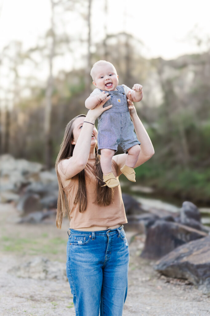 Mom holding 6 month old baby boy up while he giggles during 6 month spring milestone session with 5U Photography