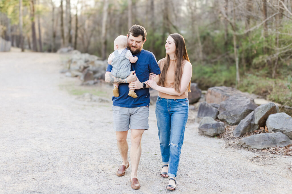 Long family walking through the park, holding hands, with baby in dad’s arms.