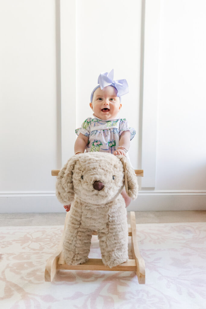 Baby Ella happily playing with a stuffed animal in her beautifully decorated nursery during her 6-month milestone shoot