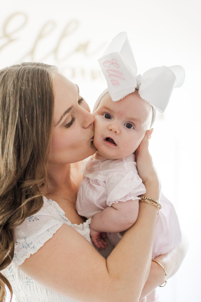 close up of mom kissing 6 month old daughter on the cheek during milestone and family session 
