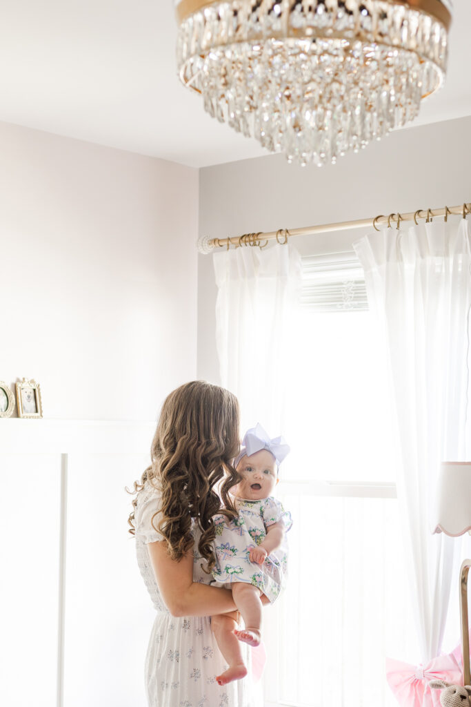 Mom smiling and holding her sweet 6-month-old baby, Ella, during her milestone session