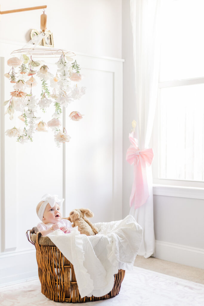 Baby Ella sitting on a cozy blanket in her nursery, smiling during her 6-month milestone session