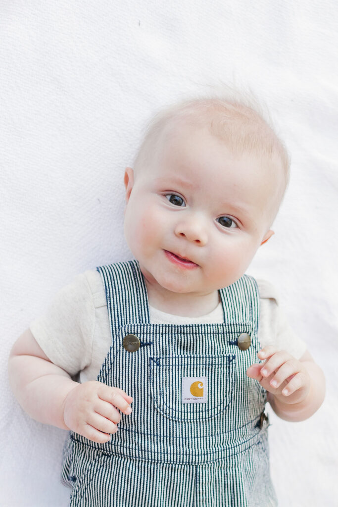 Baby smiling while sitting on a blanket in the park during the Long family milestone session