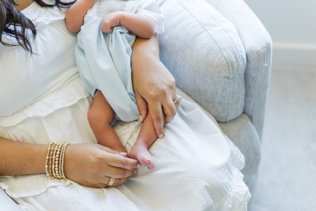Close-up of newborn baby’s tiny feet resting on mom’s lap during a Trussville, Alabama in-home newborn photography session.