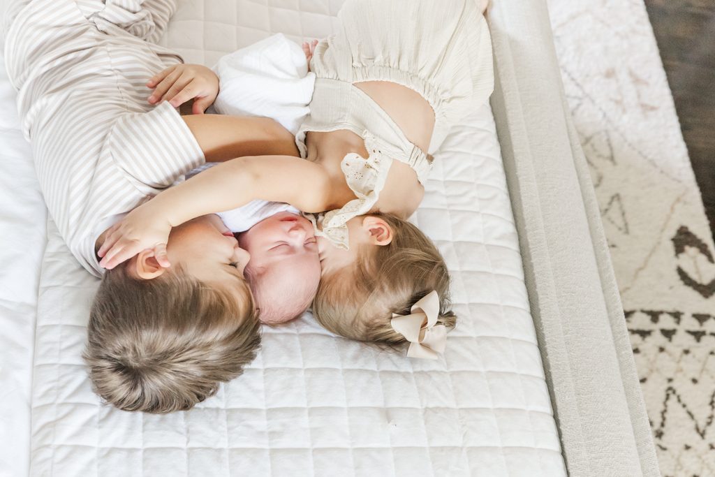 Siblings piled together around their newborn baby during an in-home newborn session