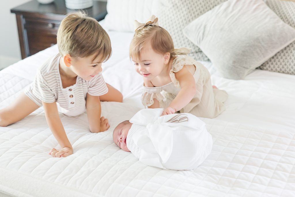 Older brother and sister loving on their newborn sibling at home in Birmingham