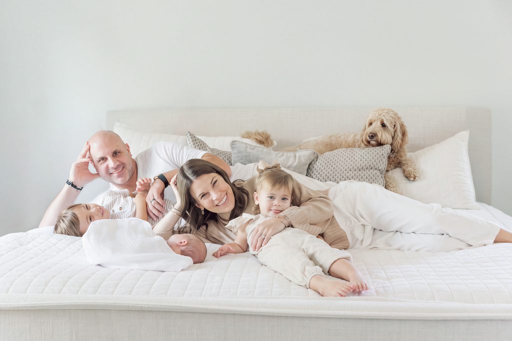 Lavender family relaxing together on the bed with their dog during their Birmingham newborn session