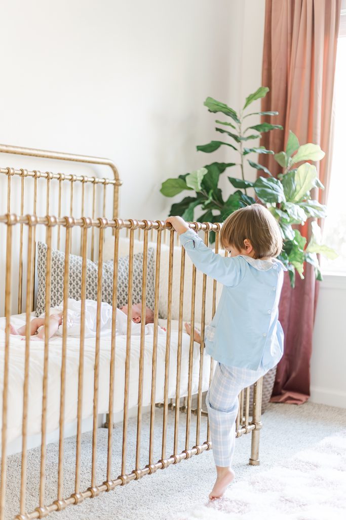 Big sister peeking into the crib during an in-home newborn session in Birmingham, Alabama