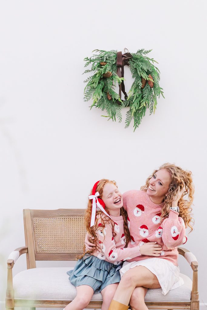 Mother and daughter smiling together during a Christmas mini photo session with festive clothing.