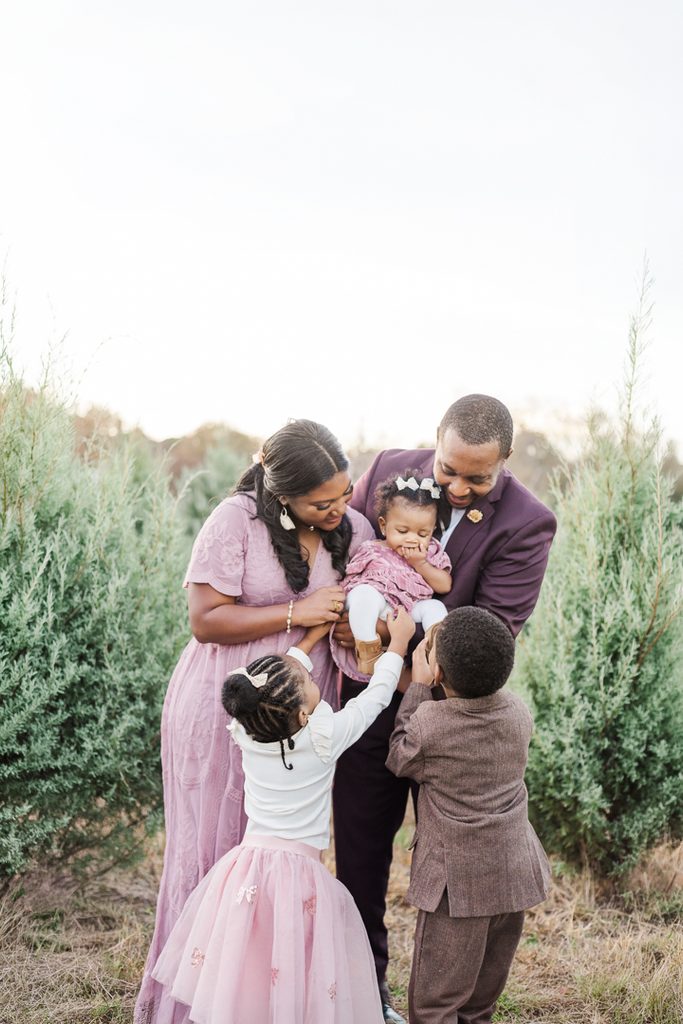 Family enjoying an affectionate moment together during a Christmas tree farm photography session.