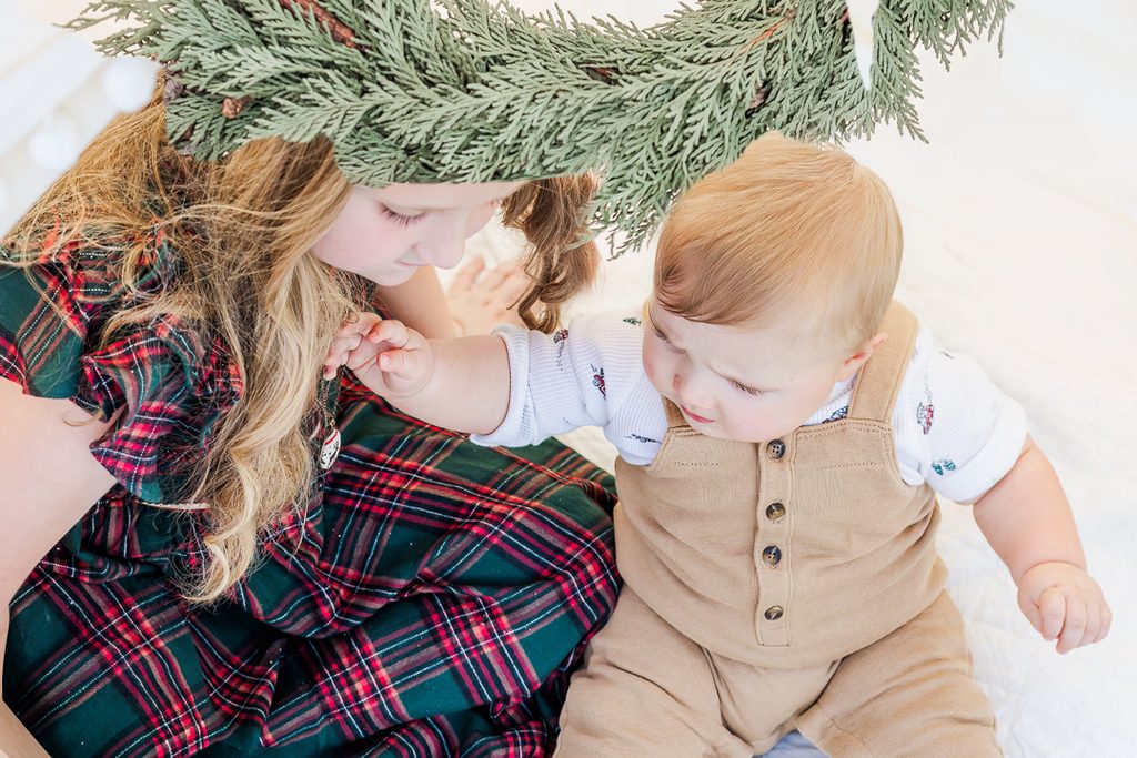 Children wearing tartan and soft neutrals in a close-up holiday portrait.
