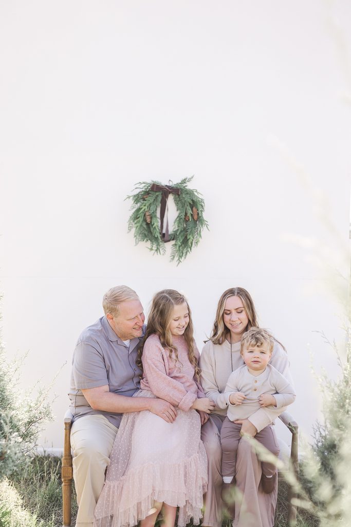Family wearing soft blush, cream and neutral Christmas outfits in an outdoor session with Burt the Reindeer.