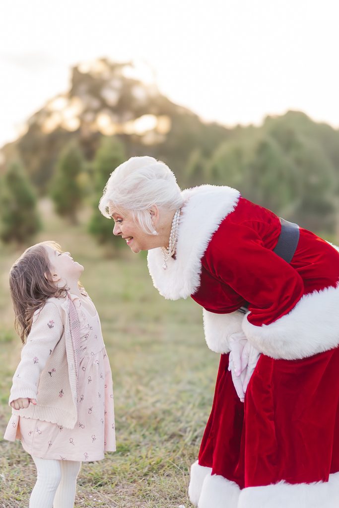 Mrs. Claus and Santa holding a baby dressed in festive red during a Christmas mini session.