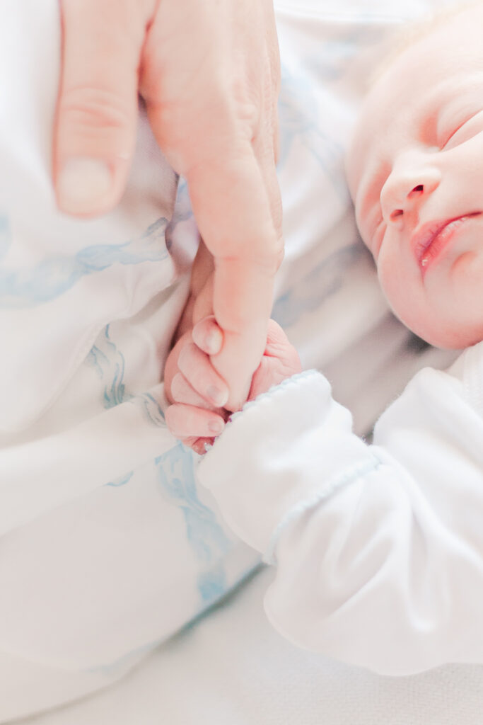 newborn holding dad's finger in hospital following delivery 