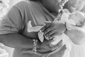 black and white picture of grandmother holding baby girl looking down and smiling during newborn session at home in Chelsea, Alabama