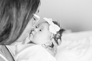 black and white image of mom holding baby up her face smiling during in-home newborn session with 5U Photography 