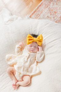 Baby girl laying asleep on blanket with hands by face during newborn photography session