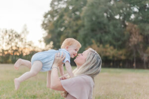 Mom holding up little boy smiling during 1 year milestone session