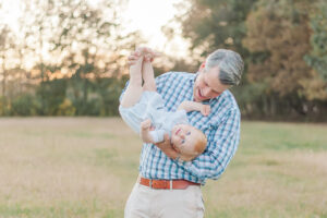 Dad holding 1 year old little boy with red hair upside down smiling during 1 year milestone and smash cake session with 5U Photography 