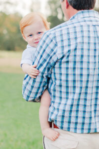 1 year old little boy looking at camera, with dad holding him during 1 year milestone and smash cake session with 5U Photography 