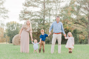 Family standing together holding hands, smiling at the camera during 1 year milestone photo session