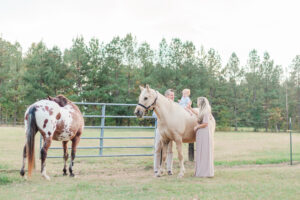 1 year old little boy sitting on horse with mom and dad standing on either side during 1 year milestone and smash cake session