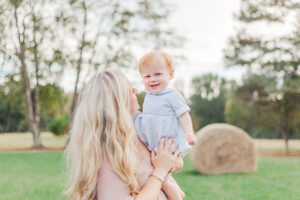 Mom holding little boy smiling at camera during 1 year milestone and smash cake session