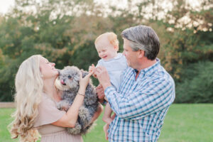 Little boy laughing down at family dog during milestone session with 5U Photography