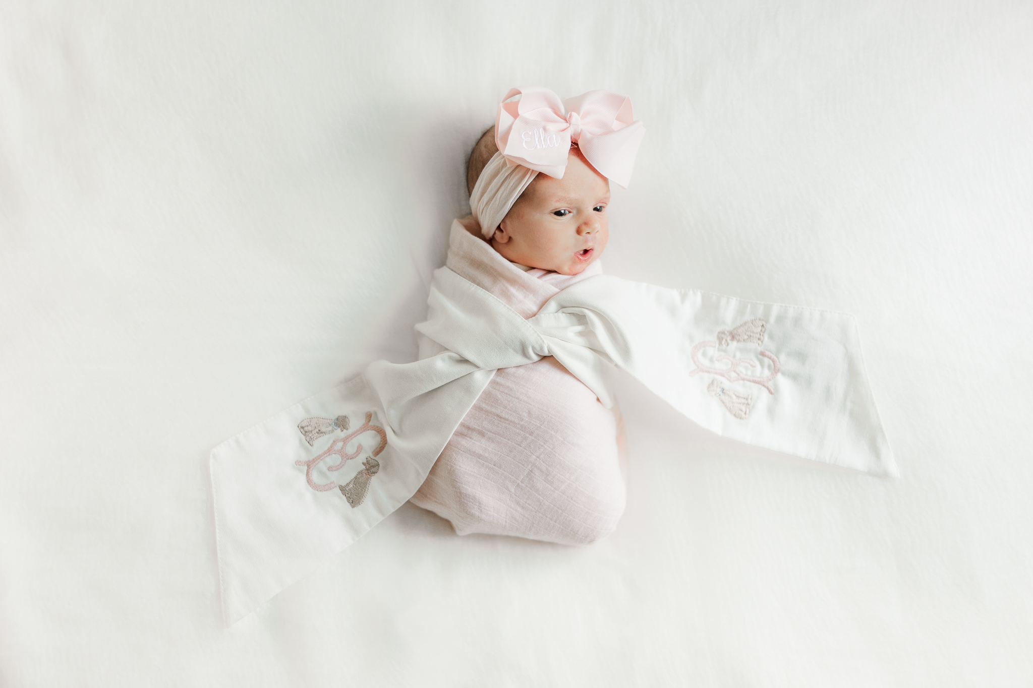 Baby girl laying on cream blanket wrapped in pink blanket during in-home newborn session in birmingham alabama