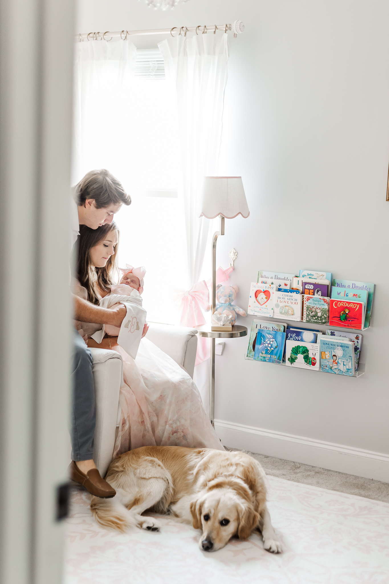 A family of three cuddling on a sofa, with the newborn nestled in the mother's arms, showcasing a warm and loving atmosphere during Birmingham in-home newborn session