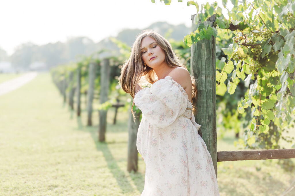 Mom leaned against fence post fixing hair during photo session with 5U Photography at Morgan Creek Vineyard