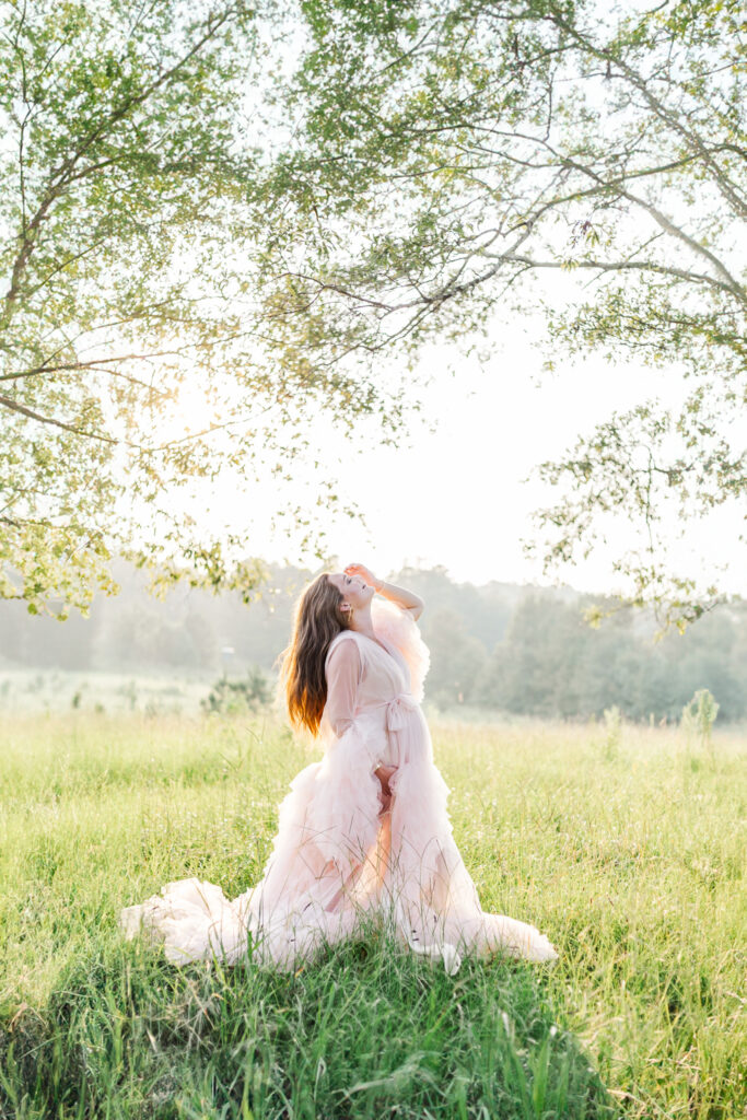 Silhouette of a pregnant woman against a vibrant sunset in a boho field, highlighting her profile and the beauty of motherhood.