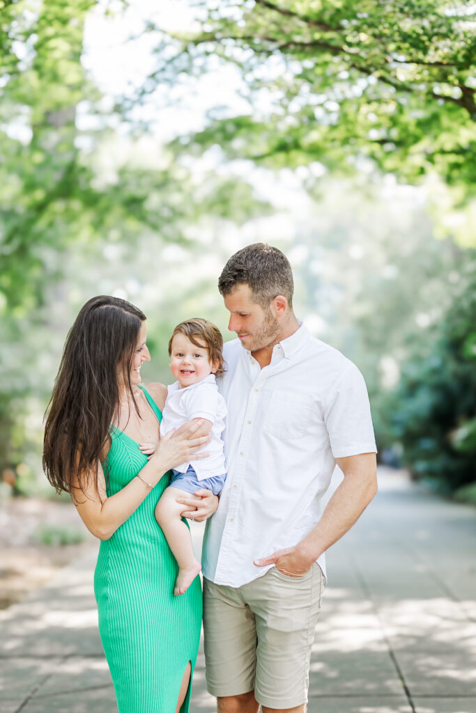 Max posing with his family, smiling happily in the beautiful setting of the Birmingham Botanical Gardens on his 1st birthday session