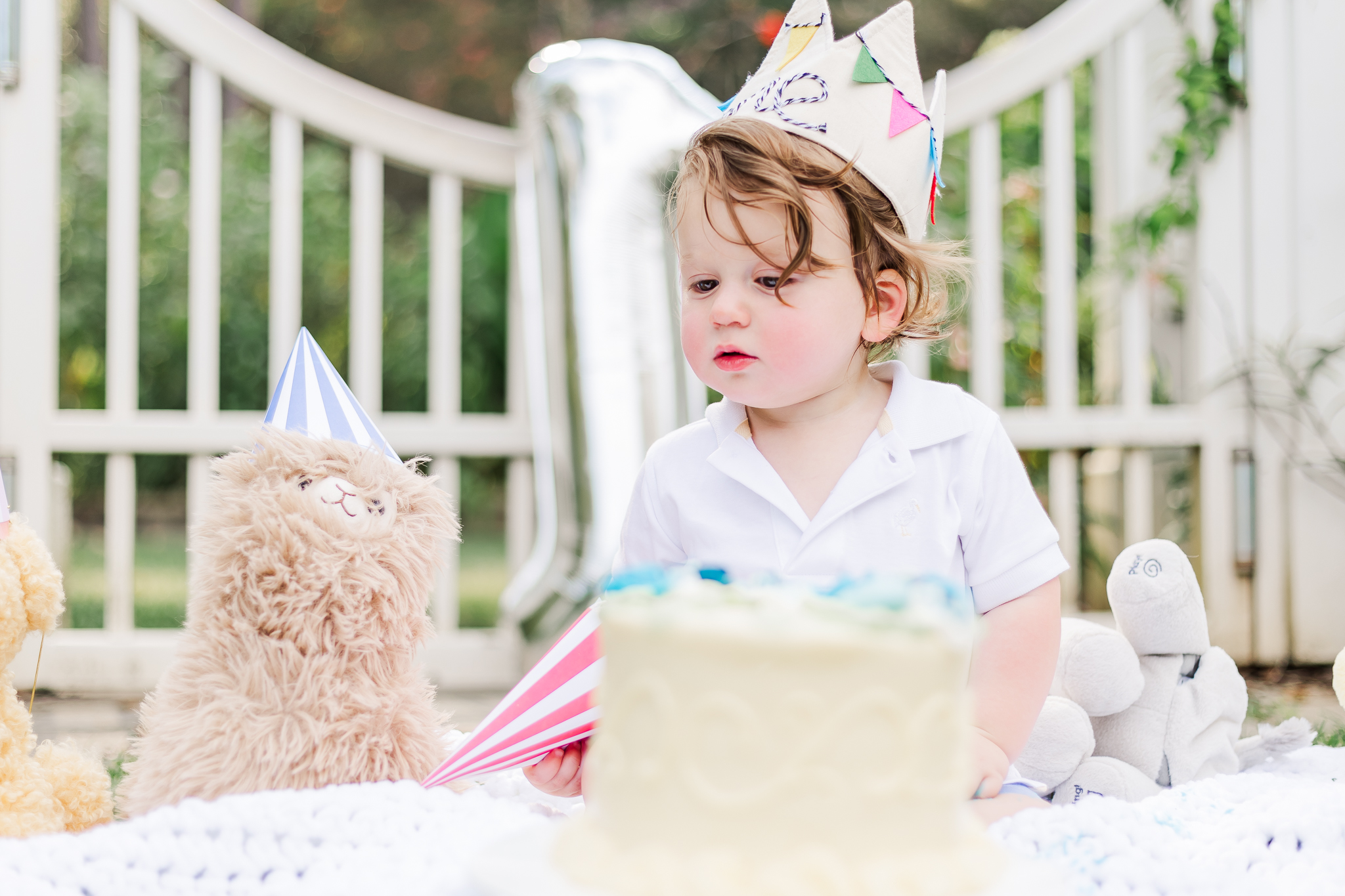 Max joyfully smashing his birthday cake surrounded by flowers at the Birmingham Botanical Gardens during 1st birthday session with 5u photography