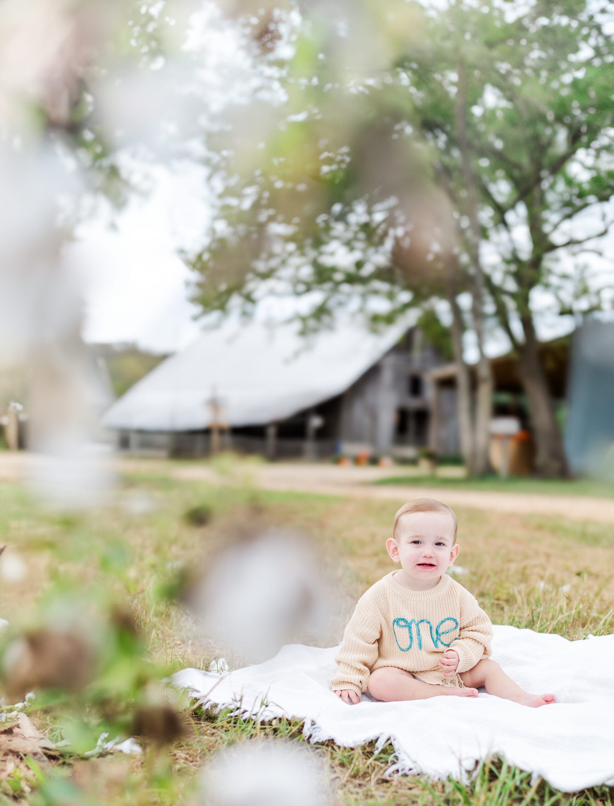 A playful moment captured of a baby crawling on a grassy field at Old Baker Farm, with a bright blue sky overhead