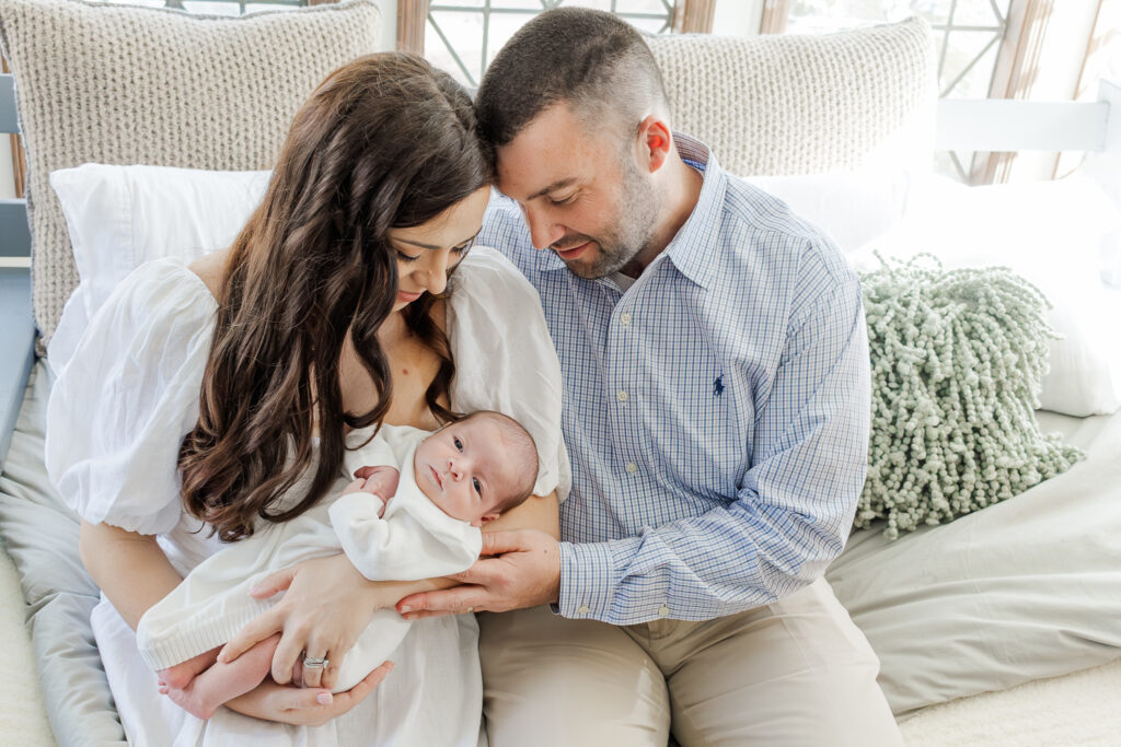 Parents lovingly gazing at their newborn baby boy in a warm, inviting living room during a lifestyle newborn session in Hoover, Alabama.