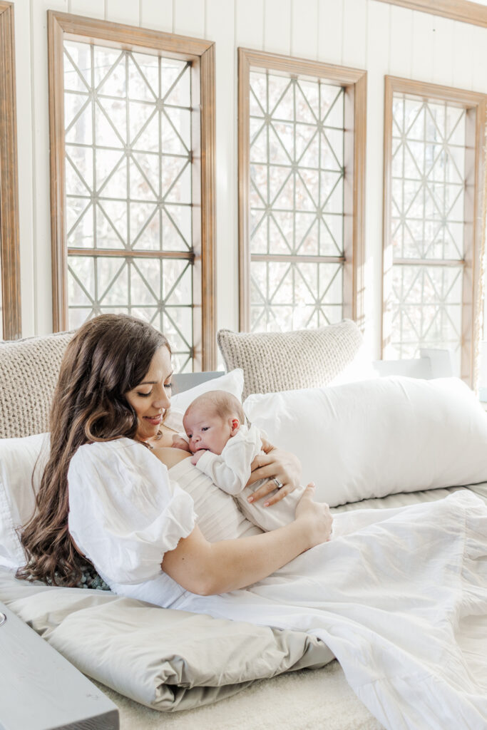 Newborn baby boy sleeping soundly in his mother's arms during in home lifestyle newborn session