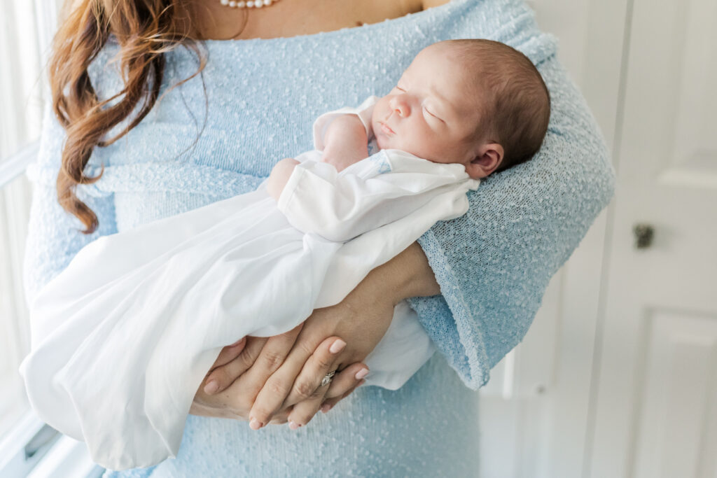 Close-up of newborn baby boy’s delicate face, with soft features and a peaceful expression, captured in natural light.